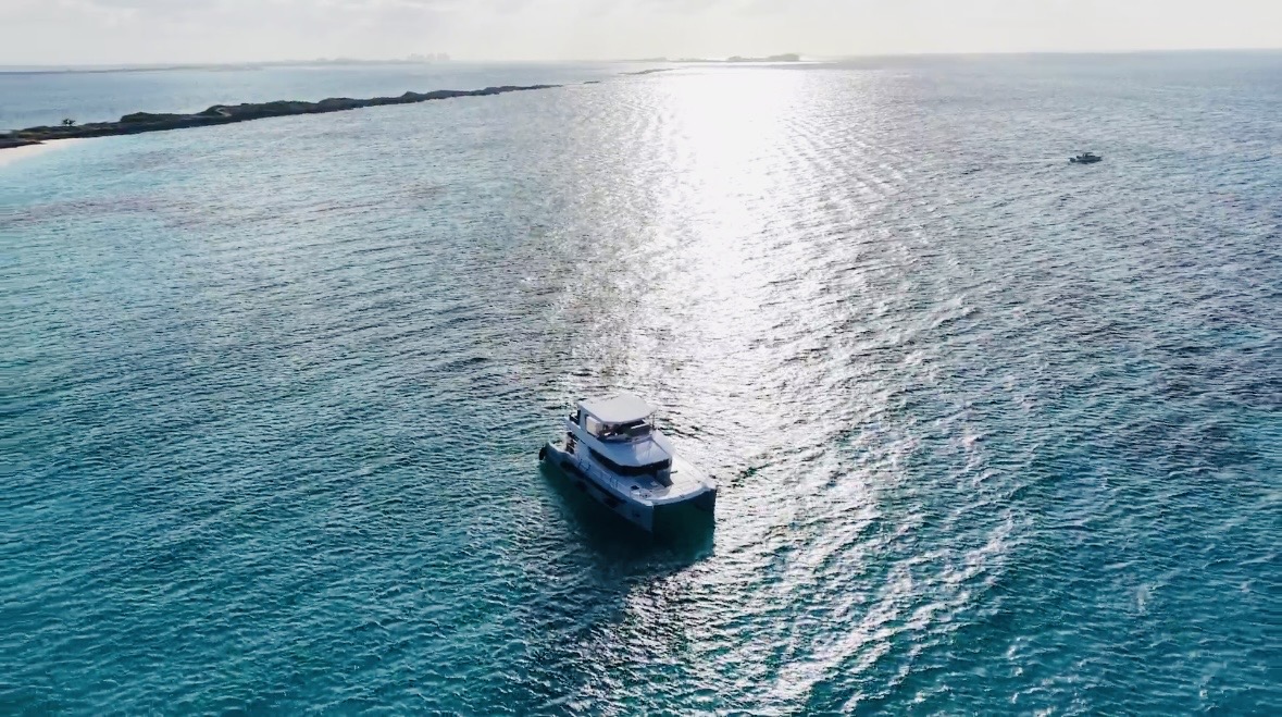 Catamaran drifting across open water at golden light