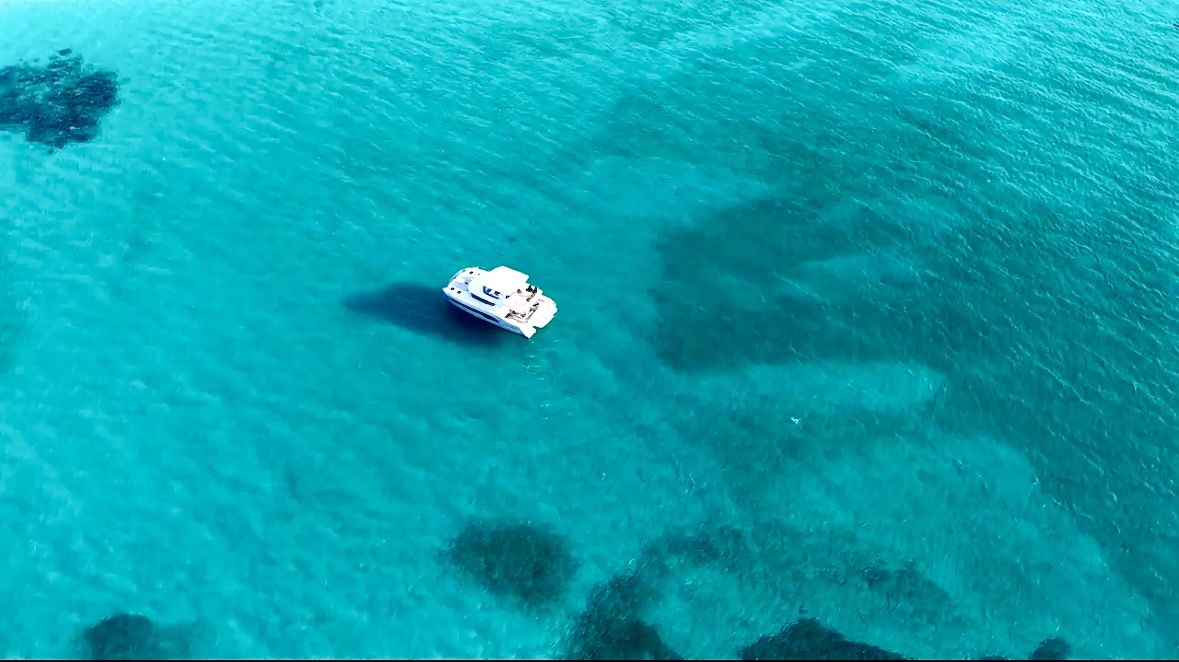 Aerial view of the yacht floating in vivid blue water