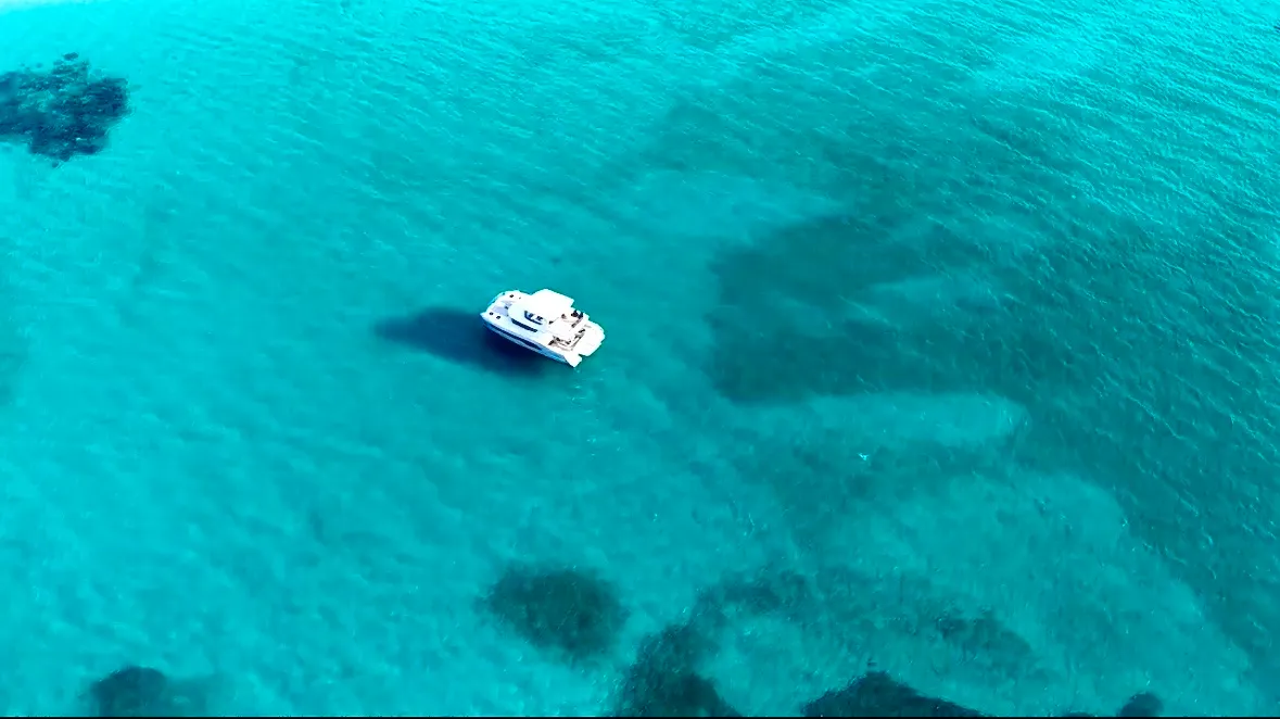 Aerial view of the yacht floating in vivid blue water