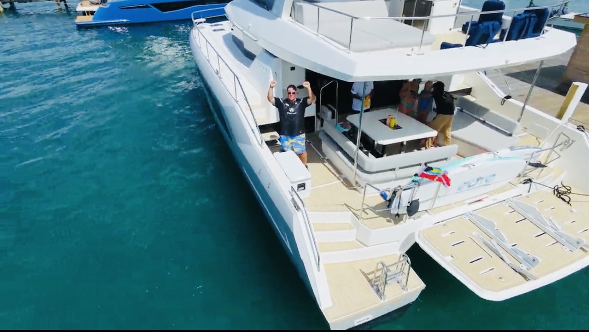 Guests waving from the aft deck of the catamaran